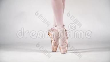 美丽的腿芭蕾舞演员在黑角的白色背景，特写。 古典舞芭蕾。 慢动作